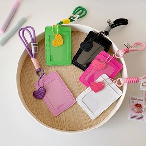 Detail of multi-color card holders with heart charms and lanyards in a wooden tray