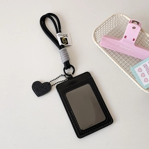 Detail of black leather card holder with neck lanyard and embossed heart pendant charm