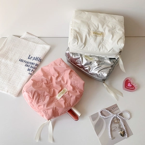 Detail of bow quilted makeup bags in pink, white and silver showing storage capacity