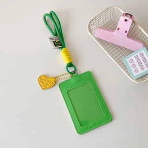 Close-up of bright green vertical card holder with woven lanyard and yellow heart charm