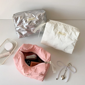 Detail of glossy bow quilted cosmetic bags with spacious interior and zipper puller
