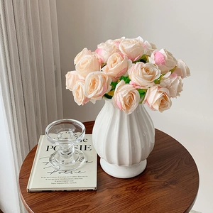 Detail of elegant faux rose pens in a white textured ceramic vase for desk decoration