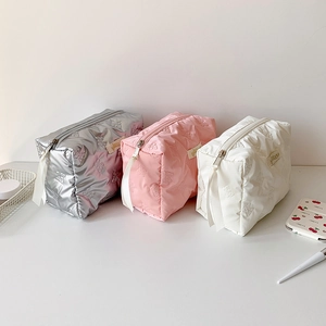 Minimalist quilted bow cosmetic bags in silver, pink, and white with ribbon zippers