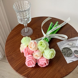 Macro detail of artificial rose pens in pink and green with a decorative ribbon