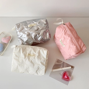 Detailed close-up of glossy makeup bags with 3D bow patterns and zip closure