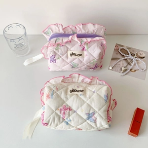 Detail of quilted butterfly pouch featuring pink ruffled edges and metal zipper closure