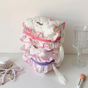 Detailed view of quilted makeup bags with butterfly prints and ruffled lace edges