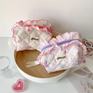 Detail of quilted floral makeup bags with ruffled edges and elegant zip closure
