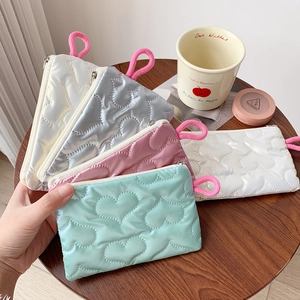 Detail of heart-quilted glossy cosmetic pouches in mint, pink, silver and white with lanyards
