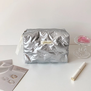Detail of silver puffy makeup bag featuring quilted butterfly patterns and metallic finish