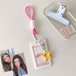 Detail of pink woven lanyard with white card holder and yellow star charm in soft lighting