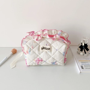 Close-up of quilted floral makeup bag with pink ruffled edges and chic fabric tag