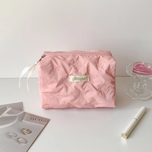 Close-up of pink quilted cosmetic bag with butterfly pattern and silk ribbon zipper