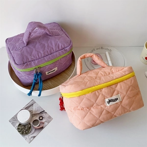 Detail of quilted checkered toiletry bag with woven tassel and side handle grip