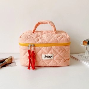 Close-up of pink checkered quilted makeup bag with yellow zipper and woven red pull cord