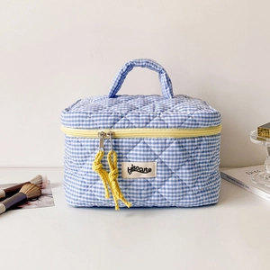 Detail of blue plaid quilted makeup bag with yellow zipper and woven knot puller