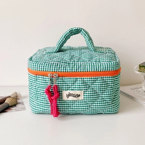 Detail of green checkered quilted cosmetic bag with orange zipper and pink cord pulls