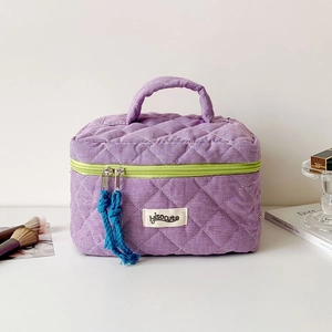 Close-up of purple checkered quilted makeup bag with lime green zipper and logo detail