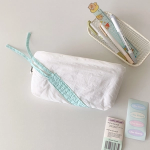 Detail of white pleated stationery bag with mint green ribbons and brand woven label