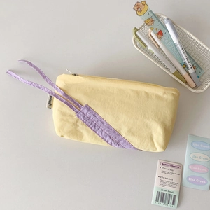 Detail of soft yellow fabric stationery bag with purple drawstring and hisocute label
