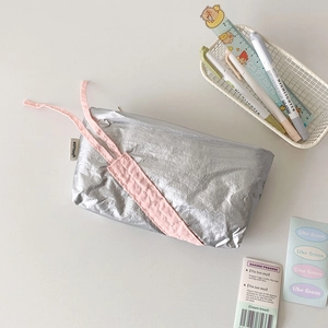 Detail of silver metallic fabric pencil case with pink ribbons and brand label