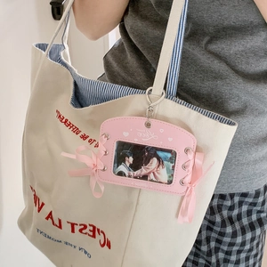 Pink ribbon bow photocard holder with metal hook displayed on a canvas bag