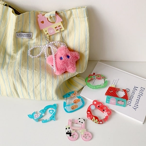 Cute acrylic cartoon carabiner keychains with panda and strawberry charms on a yellow bag