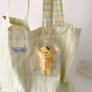 Pendentif chien en peluche jaune dans une pochette PVC transparente sur un sac rayé