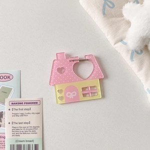 Detail of pink and yellow acrylic house-shaped charm with heart cutout and cute bow design