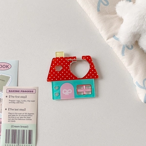 Detailed view of a cute house-shaped acrylic charm with red polka dots and blue base
