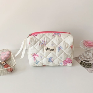 Détail de la trousse à maquillage matelassée à motifs papillons et zip rose vif