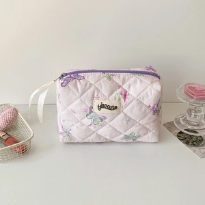 Détail d'une trousse à maquillage matelassée à motifs papillons avec ruban au curseur