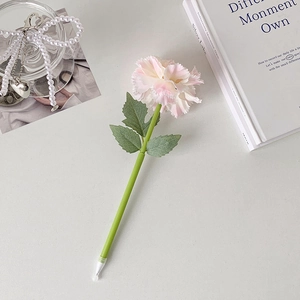 Detailed view of pink carnation ballpoint pen with green leaf stem on elegant desk