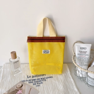 Detail of yellow mesh cosmetic bag with zipper and logo on a stylish vanity table