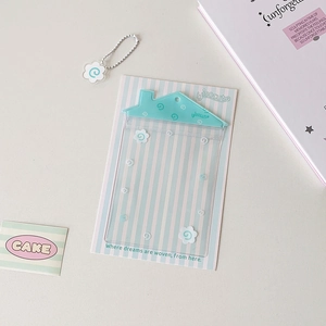 Gros plan d'un porte-carte transparent en forme de maison avec rayures bleues et fleurs