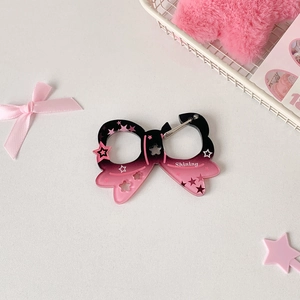 Detail of star-patterned acrylic bow charm with black and pink gradient and silver clip