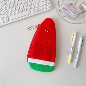 Detail of plush watermelon pencil case with funny eyes and red zipper on a desk
