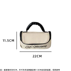 Creamy leather makeup bag with black pleated handle and 22cm size dimensions