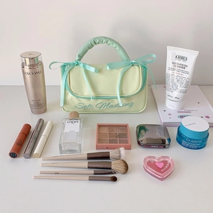Portable light green bow makeup bag with handle and soft embroidery on a white background