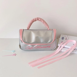 Close-up of silver and pink handheld storage bag with Soft Madeing embroidery detail