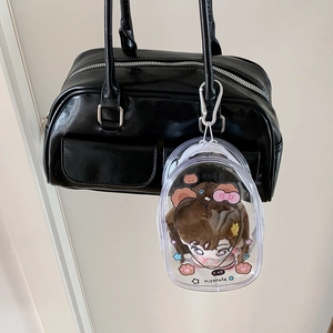 Clear oval doll display case with white strap and carabiner on a black bag