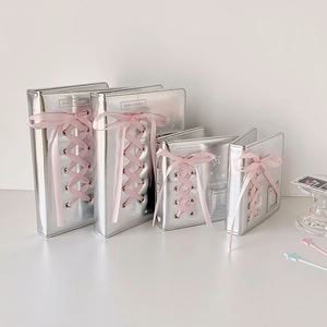 Detail of silver ballet-style photocard albums with pink ribbon lacing and glossy finish