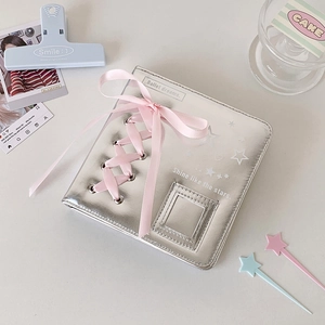 Close-up of silver leather A5 album with pink ribbon bow and star print detail