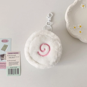 Close-up of white plush fish cake pouch with pink spiral embroidery and white clip