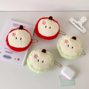 Detailed view of apple-shaped plush coin purses with metal chains on a white desk