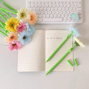 Creative sunflower pens in vibrant colors on a white desk with a keyboard and notebook