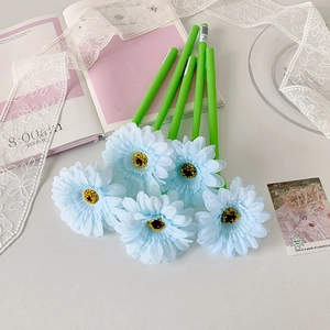 Detail of five light blue sunflower pens arranged on a pink notebook with lace