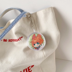 Clear circular acrylic keychain with cute anime girl illustration on white canvas bag