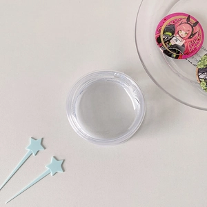 Close-up of a clear circular PVC display bag for anime badges with a snap-on lid