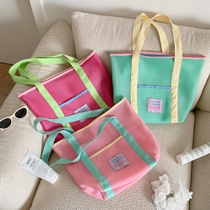 Detalle de los bolsos de playa de malla de colores con asas de cinta en contraste
